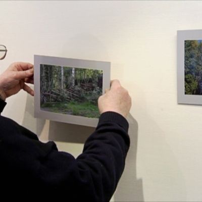 Risto Rautanen ripustamassa valokuvaa seinälle.