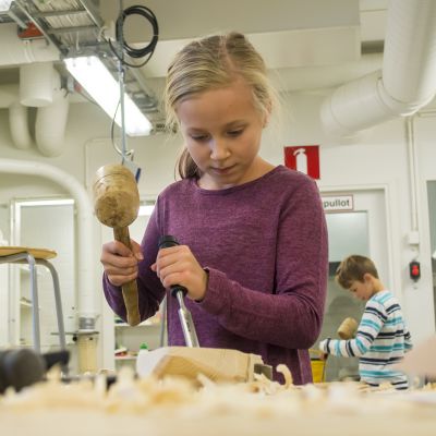 Lapsi käyttää talttaa ja vasaraa