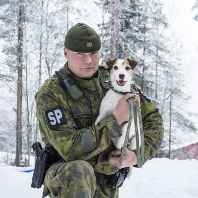 Pieni sotakoira sotilaspoliisin sylissä