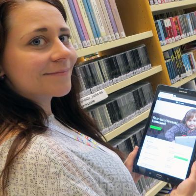 Päivi Pahkasalo kirjaston hyllyjen välissä