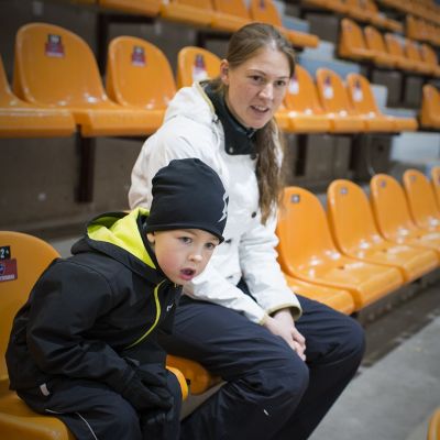 Jesper ja äiti jäähallin katsomossa.
