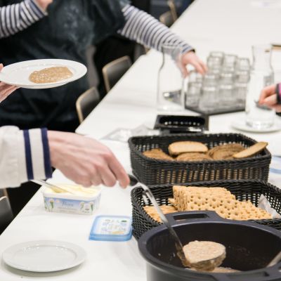 Ihmiset ottavat puuroa kattilasta.