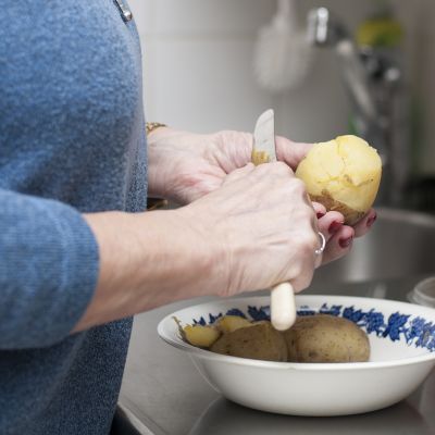 Omaishoitaja Tuula Pekonen kuorimassa perunaa.