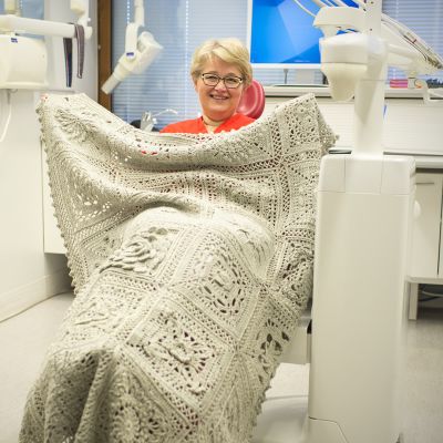 Nainen makaa Kalevapa-peitto päällään hammaslääkärin tuolissa.