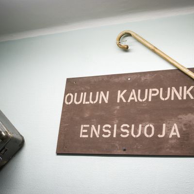 Kenttätien palvelukeskuksen seinä, jossa matkalaukku ja keppi.