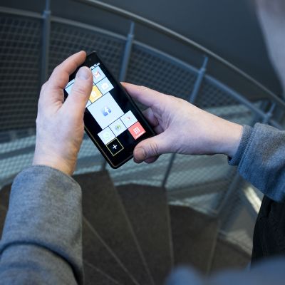 Mies katselee puhelinta jossa eri aplikaatioita.