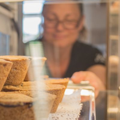 Myyjä asettelee mustikkakukkoja myymälän vitriiniin.