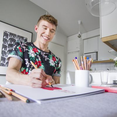 Mies piirtää keittiönpöydän ääressä.