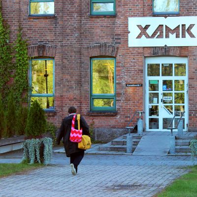 Nainen kävelee kohti Xamkin Kouvolan kampuksen pääovea