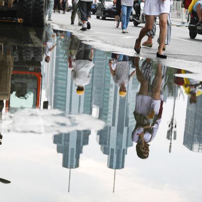 Kiinalaiset työläiset ja jalankulkijat heijastuvat vesilätäköstä.