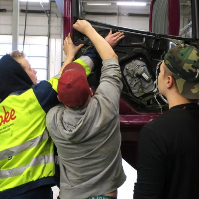 Oppilaat korjaavat kuorma-auton ovipaneelia.