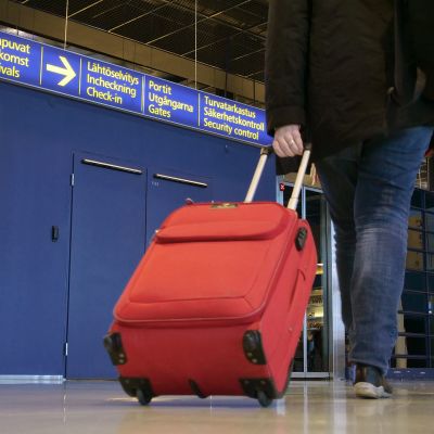 Matkustaja vetää perässään matkalaukkua lentokentällä.