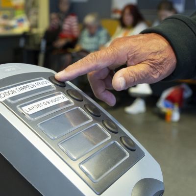 Jonotusnumerolaitteen nappia painetaan Myyrmäen terveysasemalla