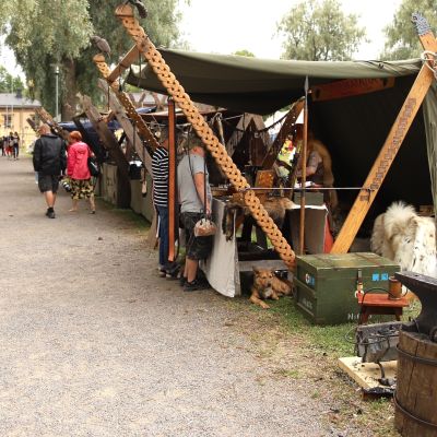 Seppä takomassa metallista esinettä Hämeenlinnan keskiaikfetivaaleilla kojunsa vieressä.