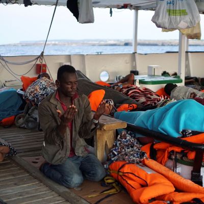 Libyan edustalta pelastettu siirtolainen rukoilee Open Arms -pelastusaluksella.