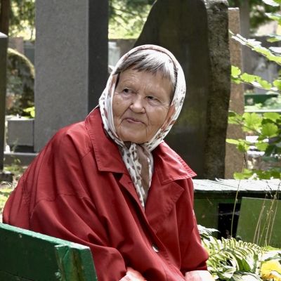 En äldre kvinna tittar över nacken på vad som händer bakom henne på den judiska kyrkogården i Vilnius.