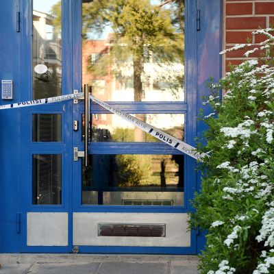 Poliisin sulkunauhaa kerrostalon alaovessa Espoon Mäkkylässä tiistaina 26. toukokuuta.