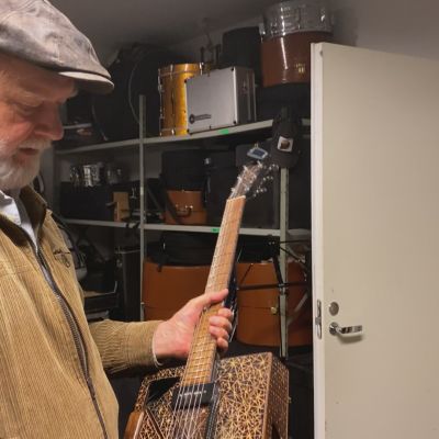 Tuomari Nurmio esittelee tärkeää instrumenttiaan, sikarilaatikko-kitaraa