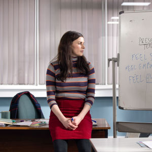 Aine (Aisling Bea) står vid en whiteboard-tavla