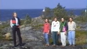 Karibiska toner vid norra Kvarken. Fem personer sjunger på en klippa.