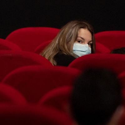 En kvinna omgiven av röda sammetsstolar i en biograf.