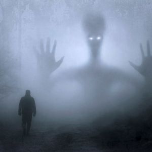 En man och ett monster i en mörk skog.
