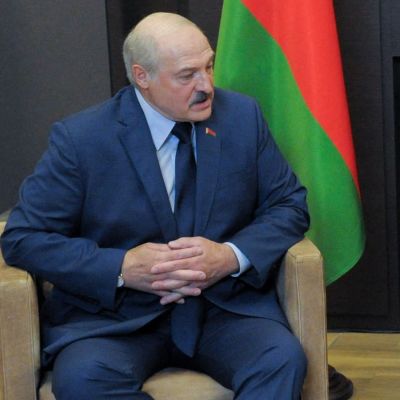 Aleksandr Lukasjenko och Vladimir Putin sitter bredvid varandra och tittar på varandra. I bakgrunden syns ländernas flaggor.