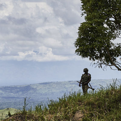 En soldat står på en grön sluttning och tittar ut över staden Beni.