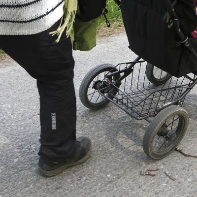 Aikuinen työntää lasta kärryissä.