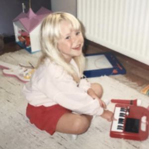 Krista har älskat att uppträda ända sedan hon var en liten flicka. Krista Siegfrids som barn spelar på leksakspiano på golvet.