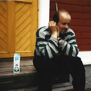 Kari Alonen istuu pajan rappusilla maitotölkin vieressä.