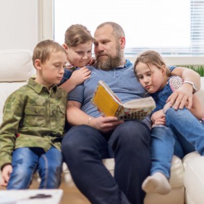 Aleksei Roganov sohvalla kolmen lapsensa kanssa.