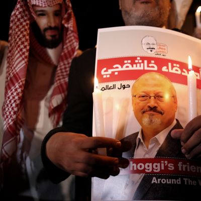 Mielenosoittaja piti Jamal Khashoggin kuvaa Istanbulissa lokakuussa 2018. Vasemmalla puolella toinen mielenosoittaja oli pukeutunut Saudi-Arabian kruununprinssiä esittävään naamariin.