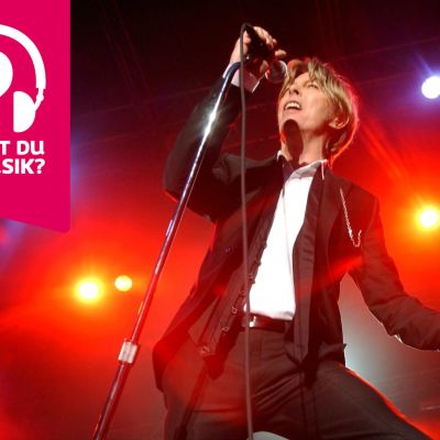 David Bowie håller i och sjunger i en mikrofon som är i en mikrofonställning.