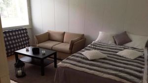 Nya hemmet. Ahmed's new home in Raseborg. Ett rum med en liten soffa, ett soffbord och en säng. Vid väggen under fönstret står en madrass luad.