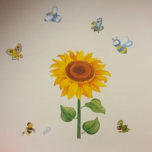 Hos terapeuten kan barn lära sig prata om blommor och insekter. Väggmålning av en solros och humlor..