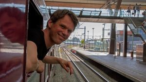 Chris Engelsman ombord på tåget. Tågresenär hänger ut genom ett fönster då tåget står på en perrong.
