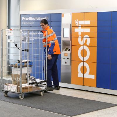 Postin työntekijä lastaa pakettiautomaattia.