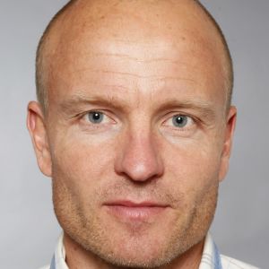 Juha-Pekka Triipponen. Juha-Pekka Triipponen, en man med skäggstubb och blåvitrutig skjorta.
