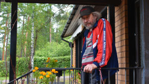 Isnäsbon Christer Alm är lättad över att hamnen ska fixas till. En man står vid ett räcke utanför en tegelstensbyggnad.