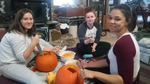 Zoe Corser, Shannon Forsberg and Varon Shepeard tillverkar prydnader av pumpor inför Halloween. Tre unga kvinnor gör Halloweenprydnader av pumpor