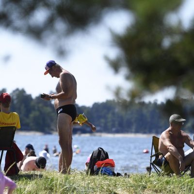 Ihmiset nauttivat lämmöstä Kallahdenniemen uimarannalla Helsingissä torstaina.
