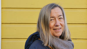 Leena Stolzmann tycker det är viktigt att konstskolan följer coronarestriktionerna (arkivbild). Medelålders kvinna står vid gul vägg.