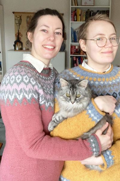 Två personer står och håller en grå katt.