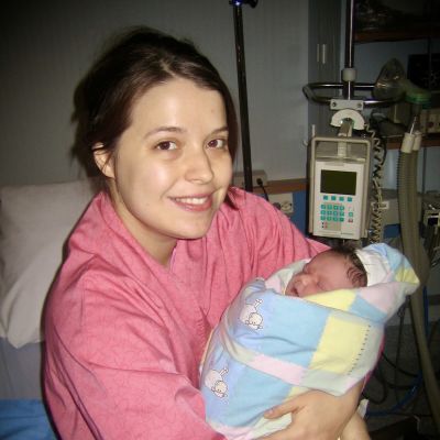 Leende kvinna med nyfödd bebis i famnen