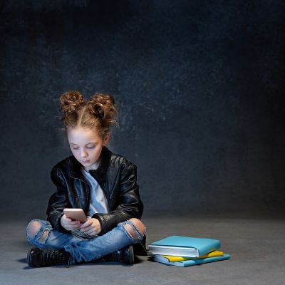 ett barn tittar på mobiltelefonen i ett mörkt rum