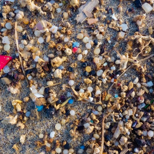 Bitar av mikroplast på en strand.