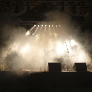 Tre mikrofoner syns på en scen bakom en rökridå