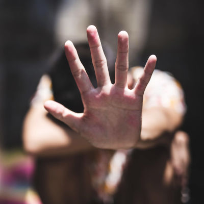 en kvinna visar stop med sin hand, handen i förgrunden, kroppen i bakgrunden