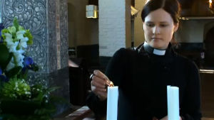 Pappi Mari Leppänen sytyttää kynttilää kirkossa, ohjelmasta A-Studio 6.3.2012